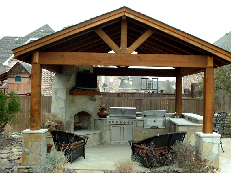 black-chairs-and-sink-in-the-right-side-of-barbecue-equipment-and-fireplace-on-the-left-and-lcd-tv-on-the-wall-also-woods