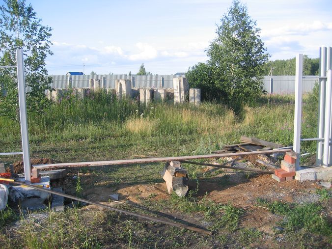 На уровень крепления ворот кладем доску. Выравниваем ее по уровню